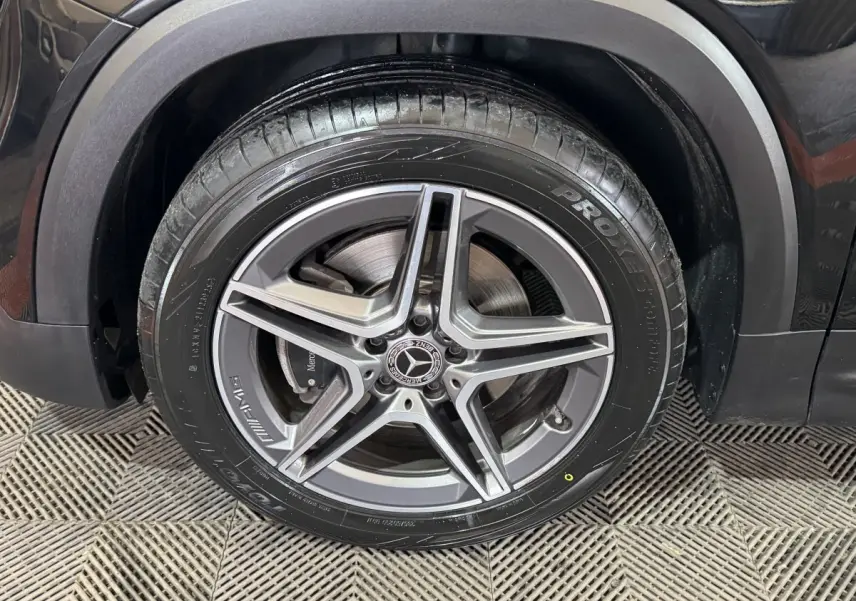Gros plan sur la roue avant droite noire d’un Mercedes GLB 200 d AMG Line avec jante alliage 5 branches.