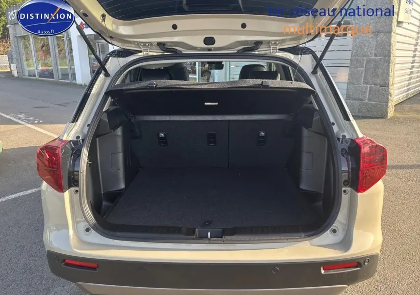 Vue arrière du Suzuki Vitara 1.4 Boosterjet Hybrid 2026 en So'Color Savanna Ivory avec coffre ouvert et hayon relevé.