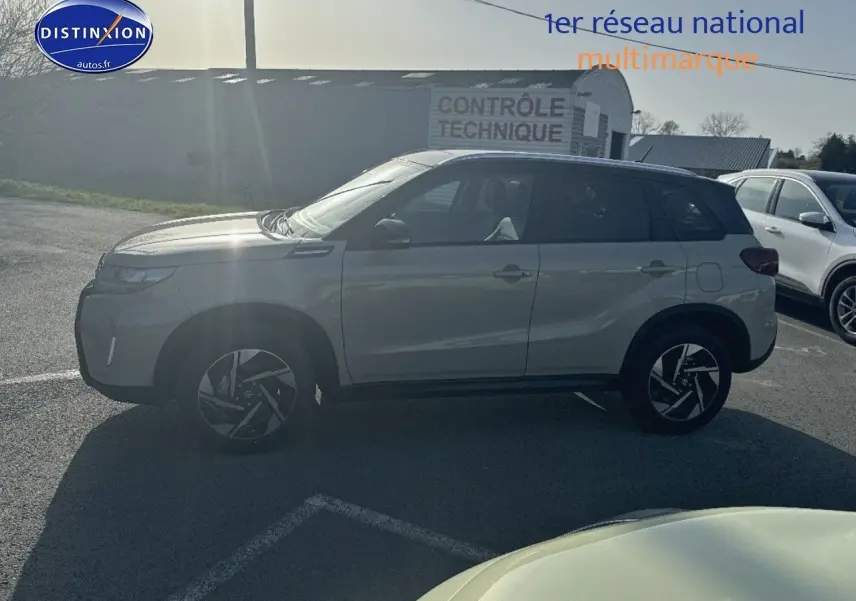 Suzuki Vitara 2026 vue de profil côté gauche, peinture bicolore ivoire et toit noir, jantes alu stylisées visibles.