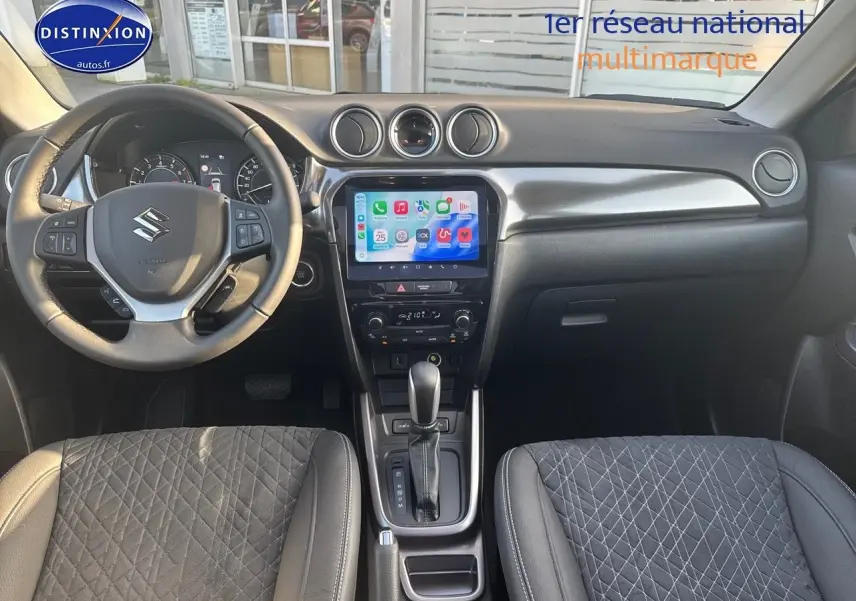 Vue intérieure avant du Suzuki Vitara 1.4 Boosterjet Hybrid, volant multifonction, écran tactile et sièges en suédine noire.