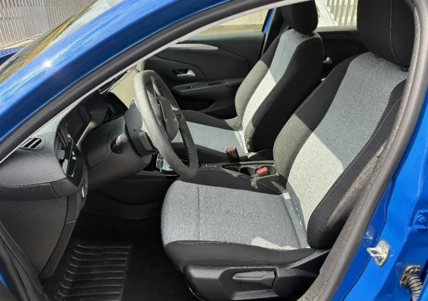 Vue intérieure côté conducteur d'une Opel Corsa 2025 bleu vif, montrant les sièges tissu bicolore et le volant.
