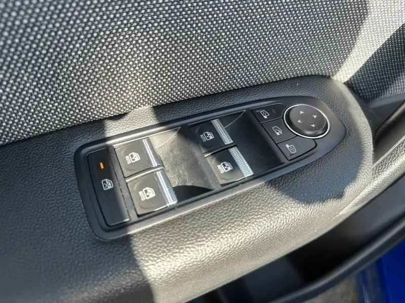 Gros plan sur les commandes de lève-vitres et rétroviseurs côté conducteur du Renault Captur 2025 Bleu Iron/Noir Etoilé.