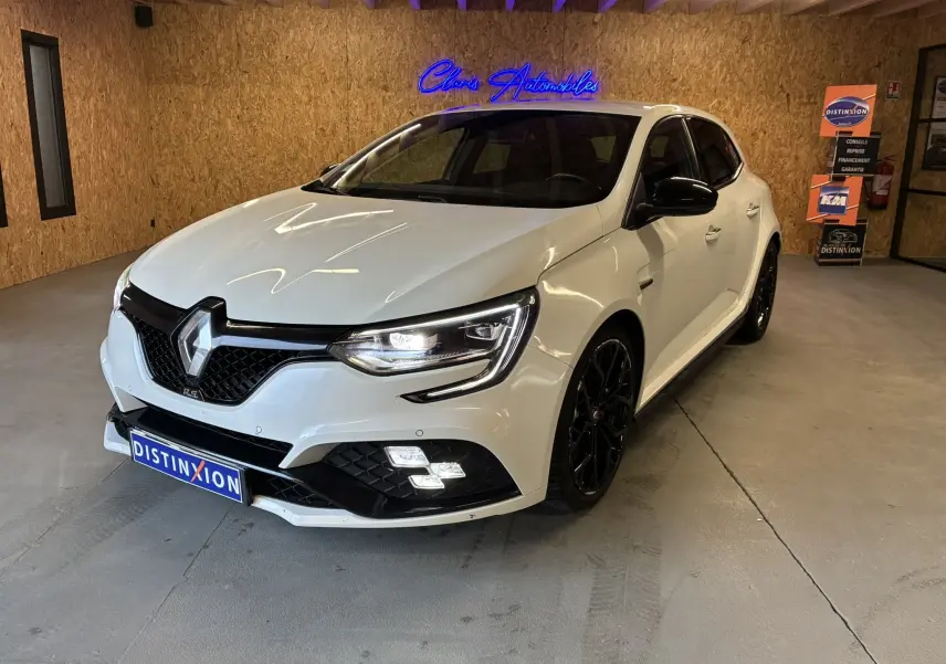 Renault Mégane IV RS 280 EDC6 blanche vue 3/4 avant droit en intérieur avec jantes noires et éclairage LED allumé.
