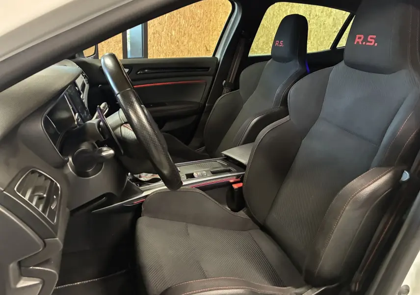 Vue intérieure côté conducteur de la Renault Mégane IV RS 280 EDC6 avec sièges sport noirs marqués R.S. en rouge.