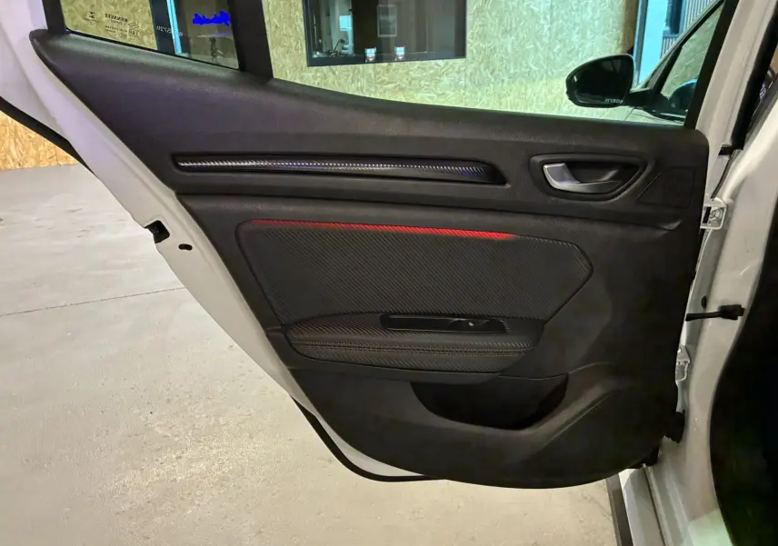 Vue intérieure de la porte arrière droite blanche d'une Renault Mégane IV RS 280 EDC6 avec insert rouge et détails carbone.