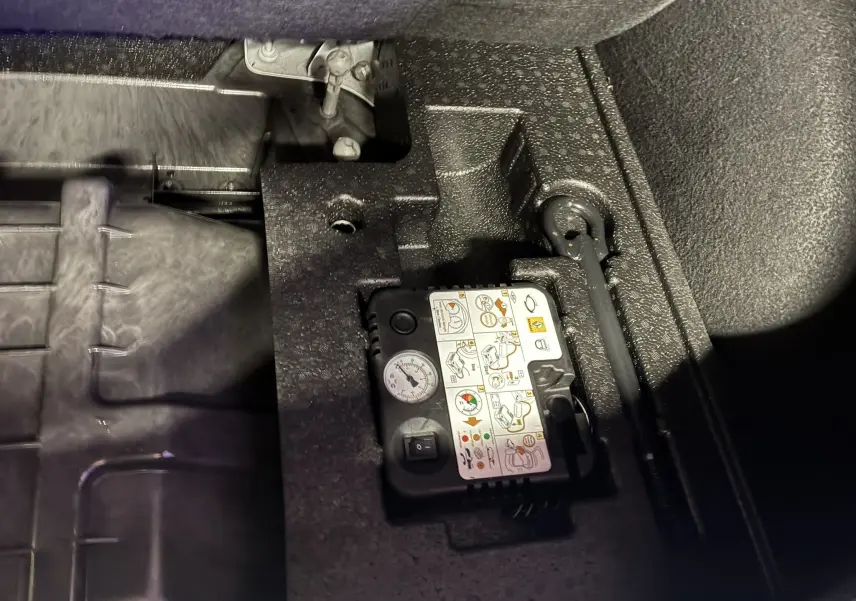 Gros plan sur le compresseur de pneu et la clé de roue dans le coffre d'une Renault Mégane IV RS 280 blanche.