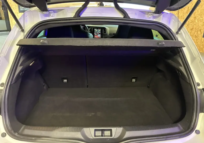 Coffre ouvert vu de l'arrière d'une Renault Mégane IV RS 280 blanche, avec tablette cache-bagages et intérieur noir.