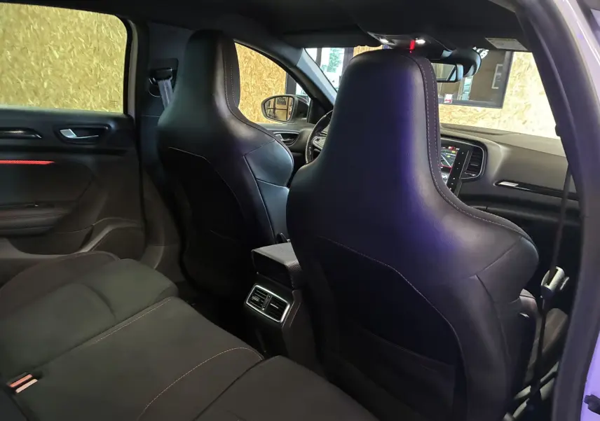 Vue intérieure arrière de la Renault Mégane IV RS 280 EDC6 2018, sièges avant en cuir noir et tableau de bord visible.