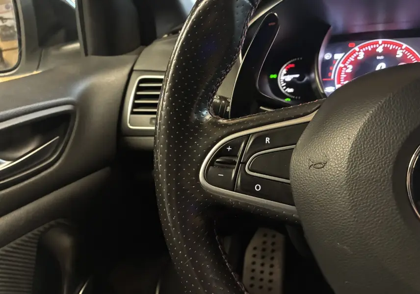 Gros plan sur le volant perforé noir et le tableau de bord éclairé de la Renault Mégane IV RS 280 EDC6.