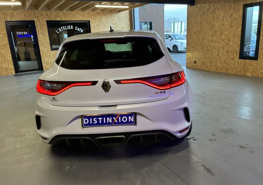 Vue arrière d'une Renault Mégane IV RS 280 EDC6 blanche, avec feux LED allumés et double sortie d'échappement centrale.