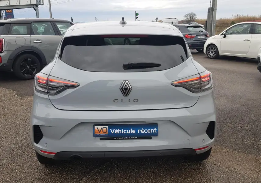 Vue arrière d'une Renault Clio gris clair 2025 avec feux LED allumés et vitres arrière surteintées.