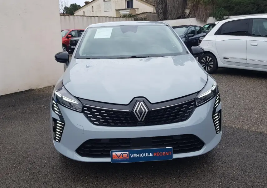 Vue frontale d'une Renault Clio gris clair 2025 avec feux LED et calandre noire distinctive.
