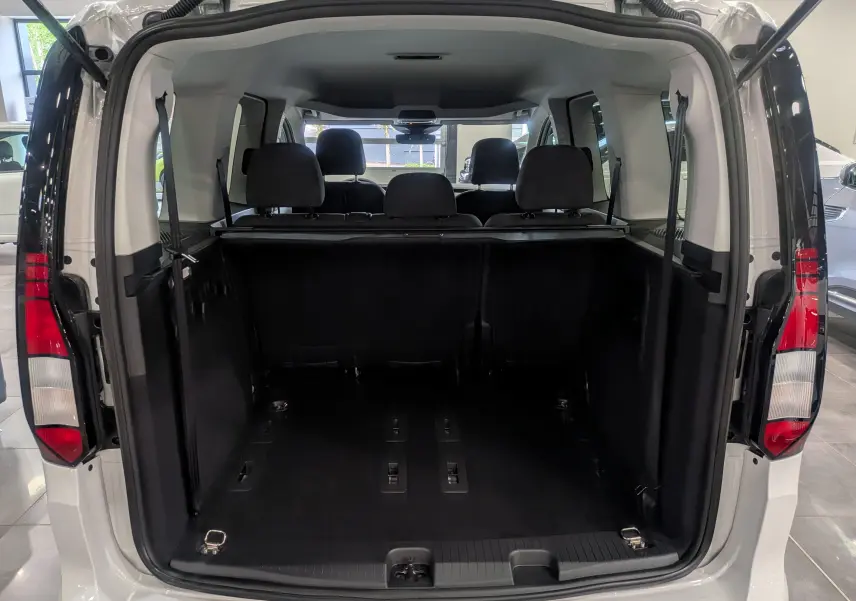 Vue arrière ouverte du Volkswagen Caddy blanc 2025 montrant l'espace de chargement et les sièges arrière noirs.