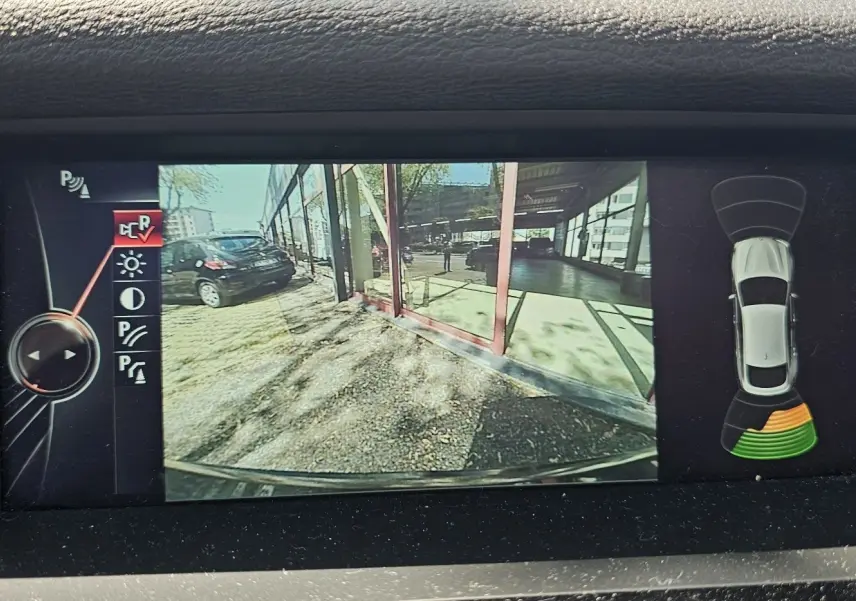 Écran de caméra de recul d'une BMW X4 xDrive20d noire, affichant l'arrière et les capteurs de stationnement actifs.