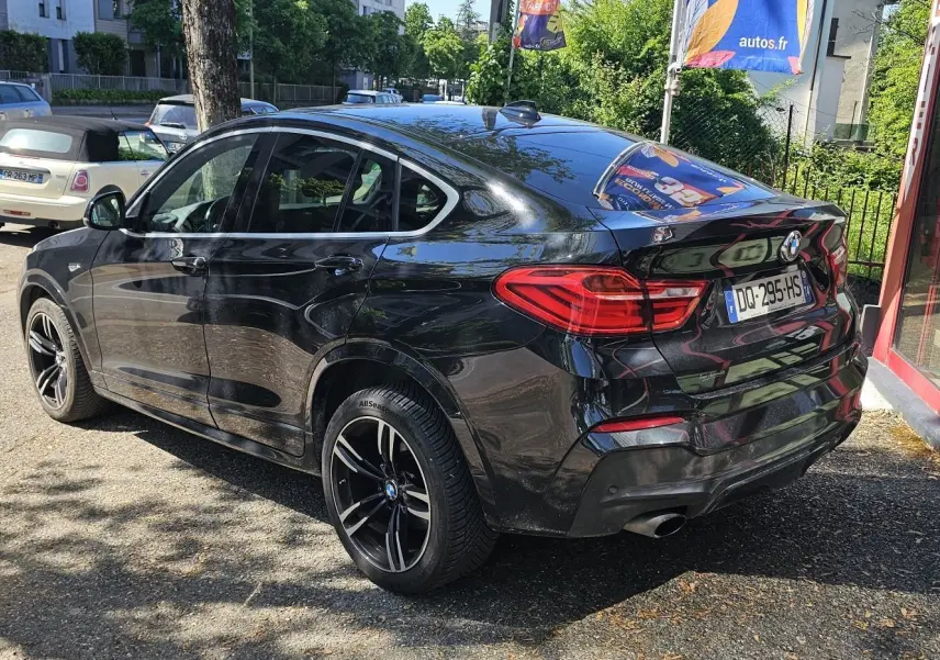 BMW X4 xDrive20dA noir vue 3/4 arrière droit, soulignant ses jantes noires et son design coupé SUV élégant.