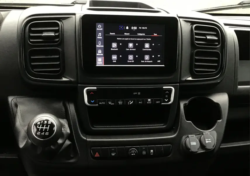 Vue rapprochée du tableau de bord du Fiat Ducato Fourgon blanc 2024, mettant en valeur l'écran tactile et le levier de vitesses manuel.