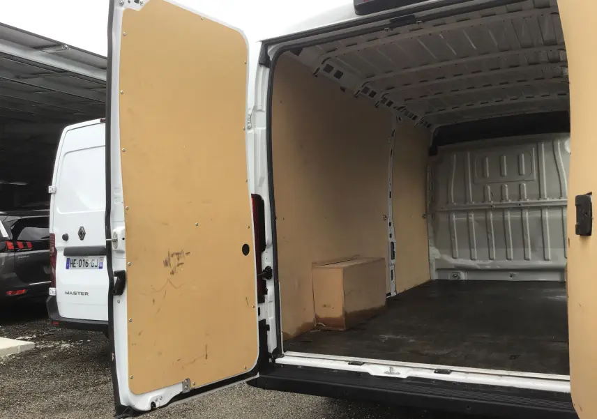 Vue arrière du FIAT Ducato Fourgon blanc 2024 avec portes ouvertes montrant l'intérieur vide et protégé par des panneaux bois.