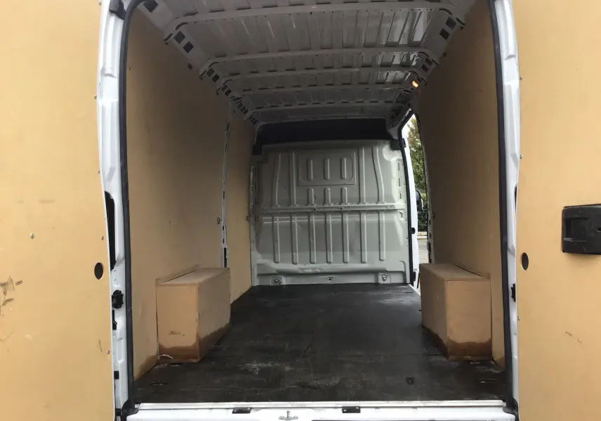 Intérieur du fourgon FIAT Ducato XLH2 blanc, vue arrière ouverte montrant l'espace de chargement vide et les parois boisées.