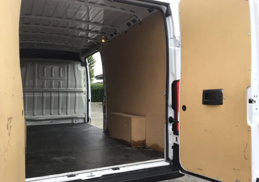 Vue arrière ouverte du FIAT Ducato Fourgon blanc 2024, montrant l'intérieur spacieux avec parois en bois clair.