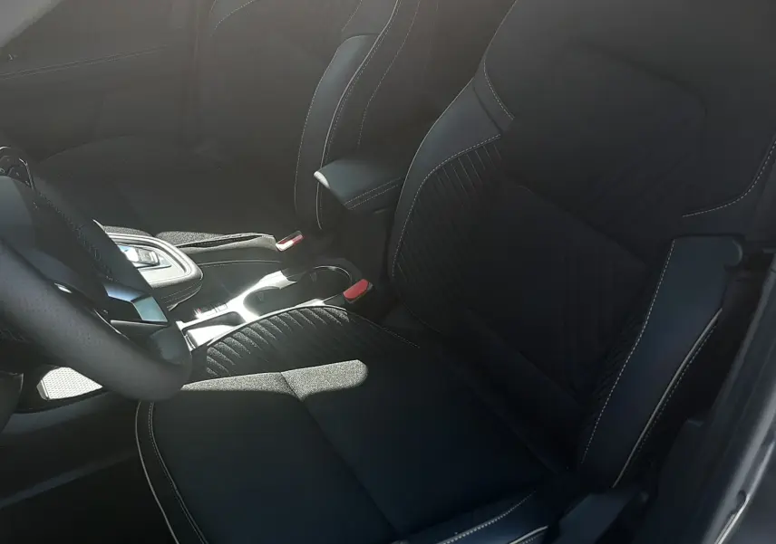 Vue intérieure côté conducteur du Renault Symbioz 2025, sièges noirs avec surpiqûres contrastantes et console centrale moderne.