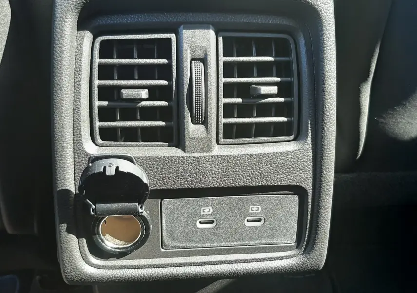 Détail de la console arrière avec prises USB-C et prise allume-cigare ouverte dans un Renault Symbioz gris Cassiopée.