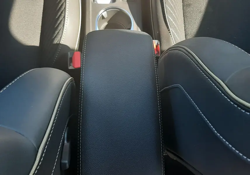Vue plongeante sur l'accoudoir central noir avec surpiqûres blanches entre les sièges avant du Renault Symbioz gris Cassiopée.