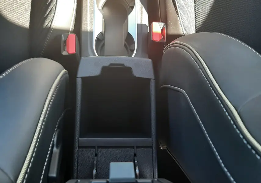 Vue plongeante sur la console centrale noire et les sièges en tissu noir avec surpiqûres blanches du Renault Symbioz hybride.