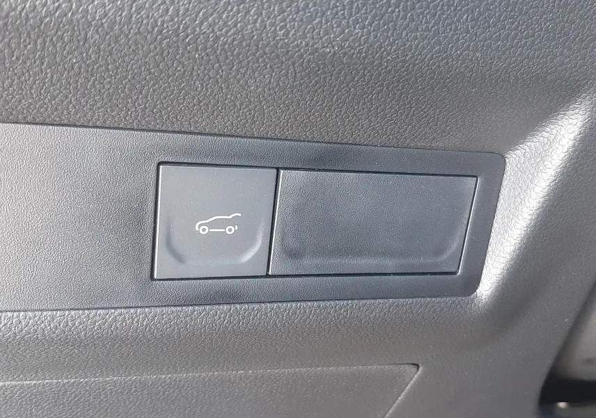 Bouton d'ouverture du coffre sur tableau de bord noir du Renault Symbioz E-Tech Full Hybrid gris Cassiopée.