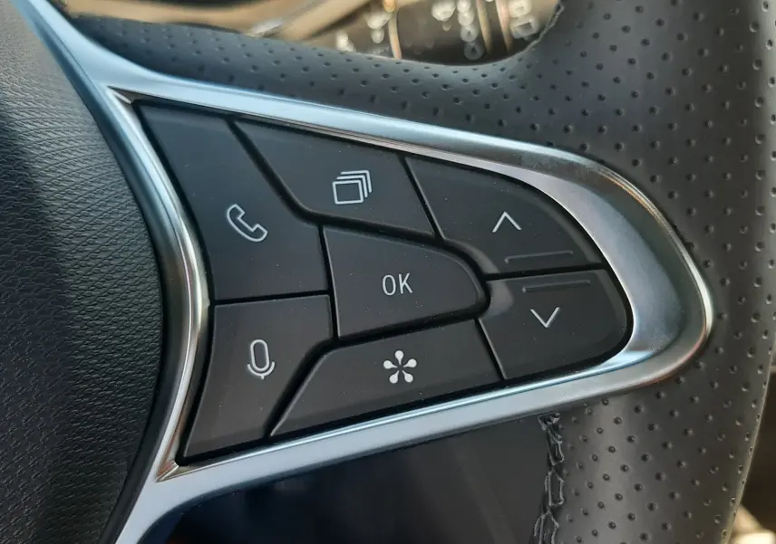 Gros plan sur les commandes multifonctions à gauche du volant perforé du Renault Symbioz gris Cassiopée 2025.