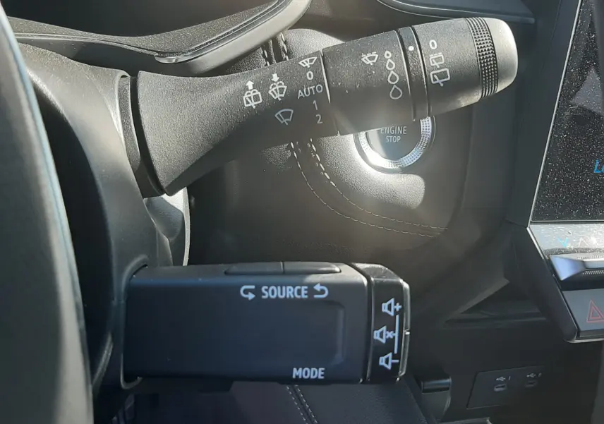 Gros plan sur les commandes au volant et bouton start/stop du tableau de bord noir du Renault Symbioz gris Cassiopée 2025.