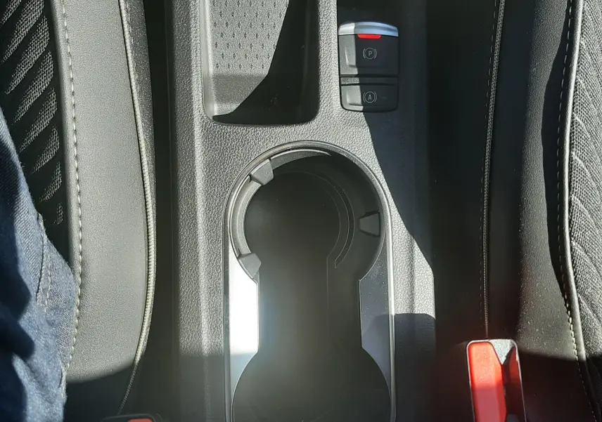 Gros plan sur la console centrale noire du Renault Symbioz 2025, avec porte-gobelets et boutons de frein à main électrique.