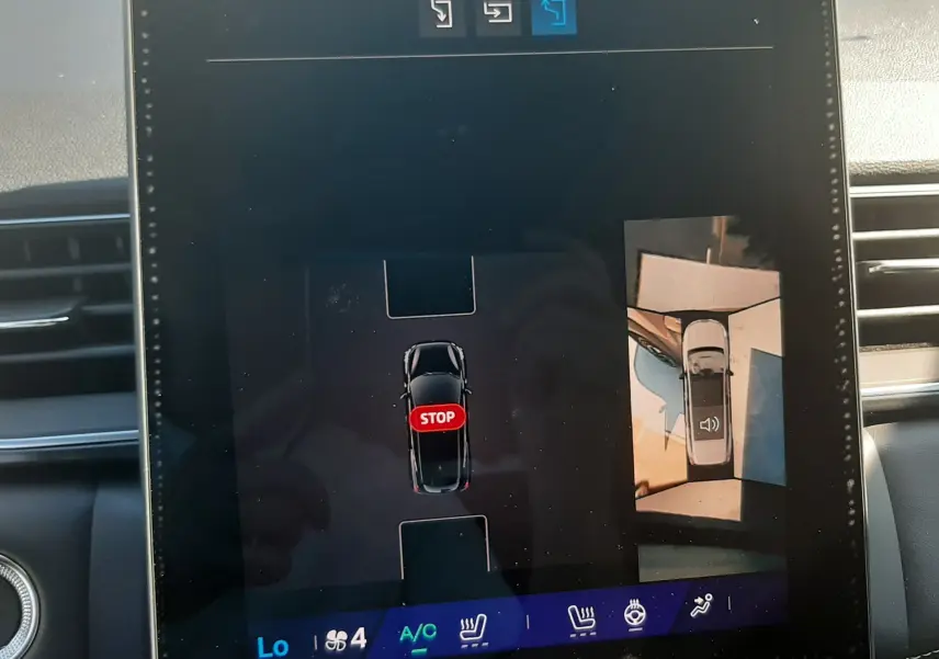 Écran tactile intérieur du Renault Symbioz gris cassiopée montrant l'aide au stationnement avec vue aérienne du véhicule.