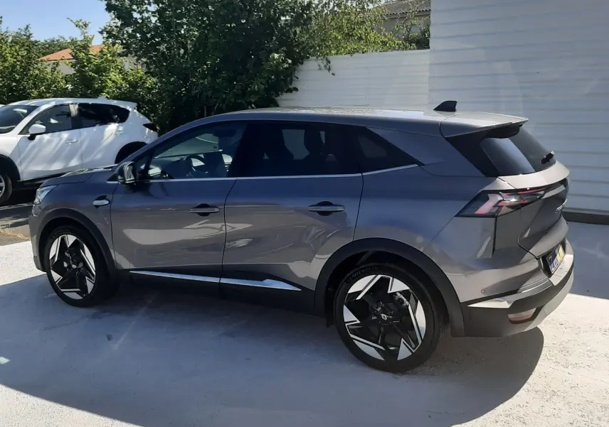 Renault Symbioz E-Tech gris cassiopée vu de profil côté gauche, avec jantes noires et détails chromés.