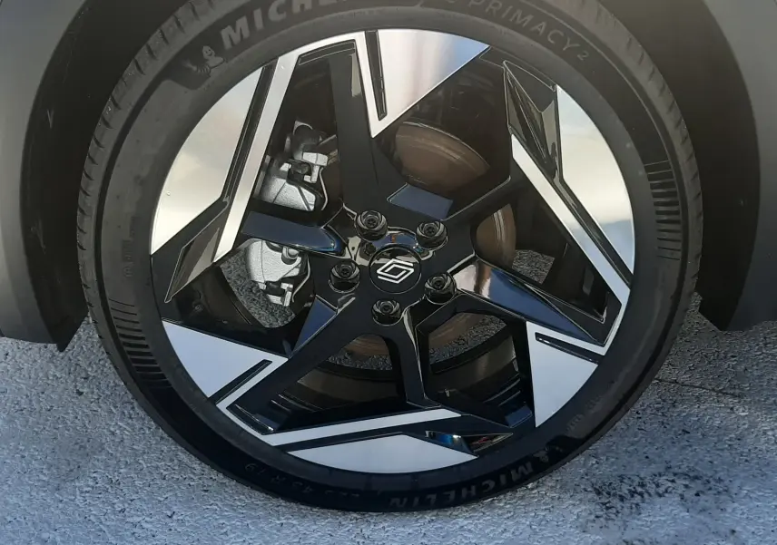 Gros plan sur la roue avant droite du Renault Symbioz gris Cassiopée, jante alliage noir et argent au design moderne.