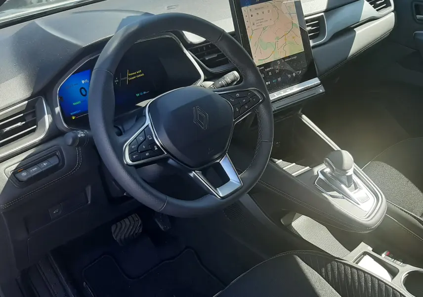 Intérieur Renault Symbioz E-Tech hybride 2025 vu côté conducteur, tableau de bord noir avec écran tactile vertical et volant multifonction.