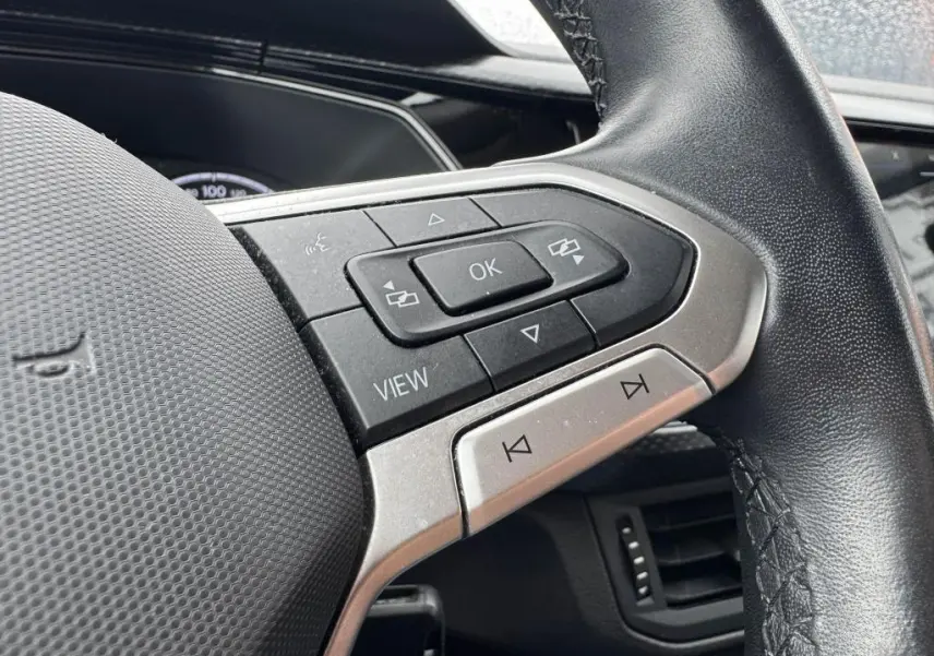 Gros plan sur les commandes multifonctions côté gauche du volant en cuir noir du Volkswagen T-Cross orange 2021.