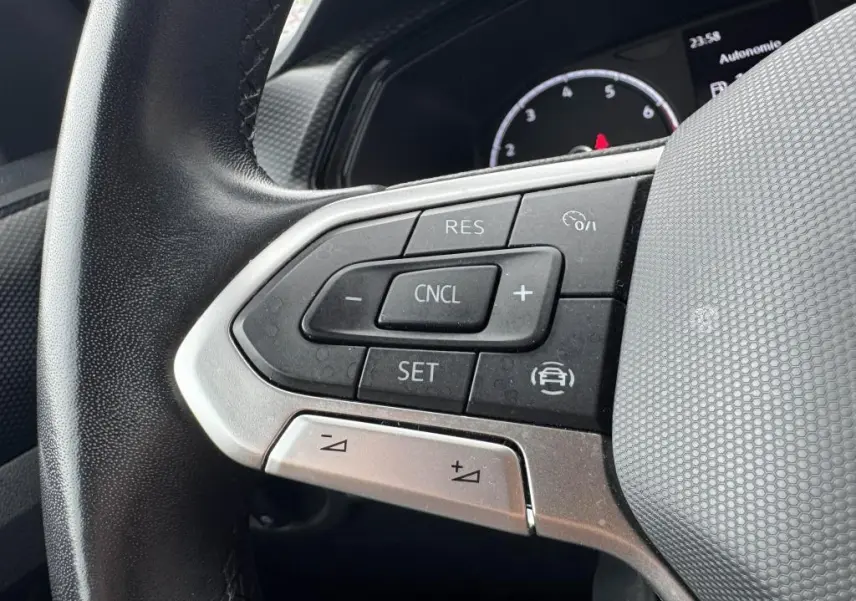 Gros plan sur les commandes de régulateur de vitesse au volant cuir noir du Volkswagen T-Cross orange 2021.