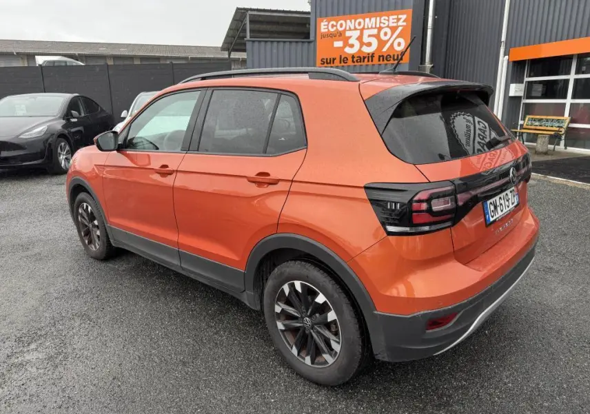 Volkswagen T-Cross orange métallisé vue 3/4 arrière droit avec jantes Galway et feux arrière noirs.