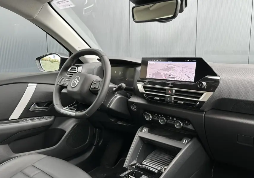 Intérieur avant droit de la Citroën C4 Manhattan Green 2025, tableau de bord avec écran tactile et volant cuir noir.