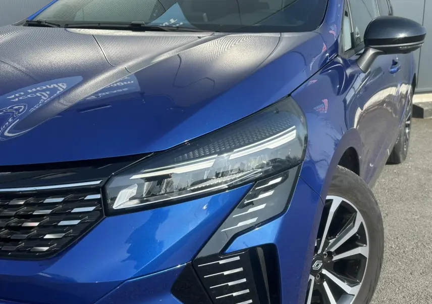 Gros plan sur l'avant droit de la Renault Clio 2025 Bleu Iron, mettant en valeur ses phares LED et la calandre moderne.