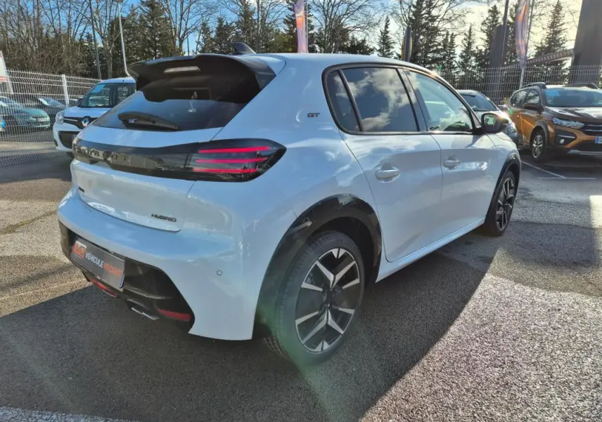 Vue 3/4 arrière droite d'une Peugeot 208 Hybrid 136 GT blanche avec jantes alliage 17 pouces et feux arrière LED distinctifs.