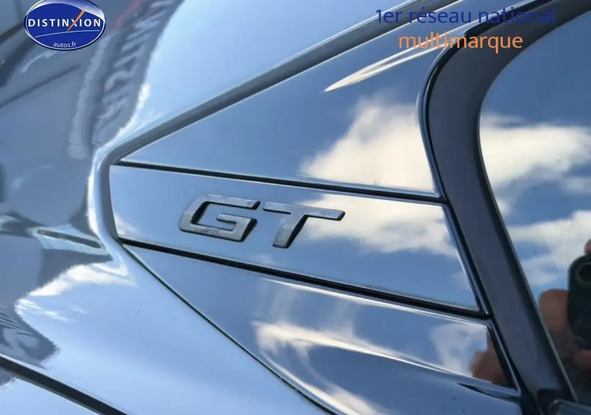 Gros plan sur l’inscription GT en relief sur la carrosserie gris titane d’une Peugeot 508 Hybrid 225 gt e-eat8.