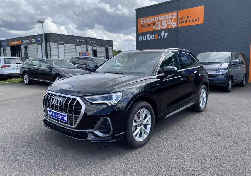 Audi Q3 noir intense métallisé vue 3/4 avant droit sur parking avec calandre chromée et jantes argentées.