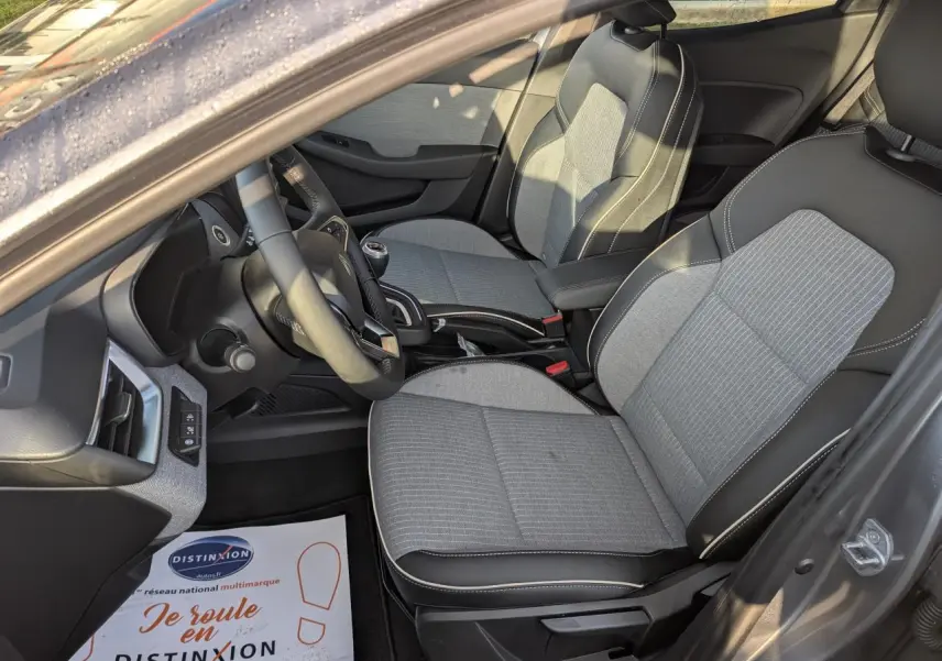 Intérieur avant droit de Renault Clio gris schiste 2025 avec sièges tissu gris et volant multifonction.