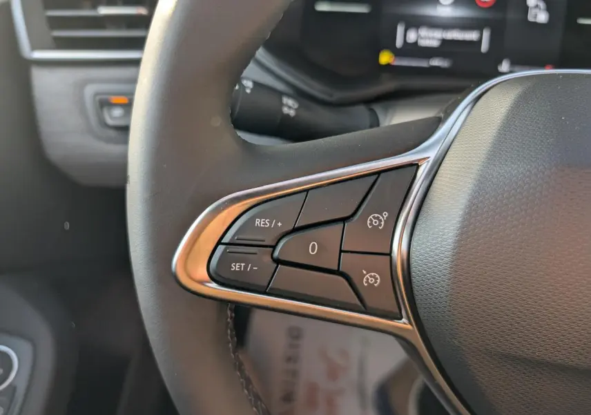 Gros plan sur les commandes du régulateur de vitesse au volant de la Renault Clio 2025 finition Techno.