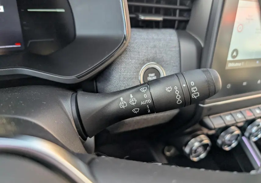 Gros plan sur la commande d'essuie-glace à gauche du volant dans l'habitacle gris mélangé de la Renault Clio 2025.