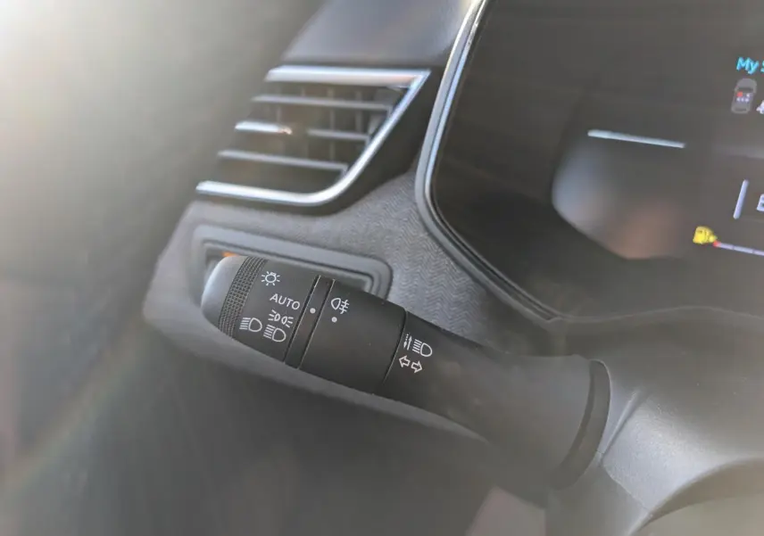 Gros plan sur la commande des feux et clignotants à gauche du volant dans une Renault Clio gris schiste 2025.