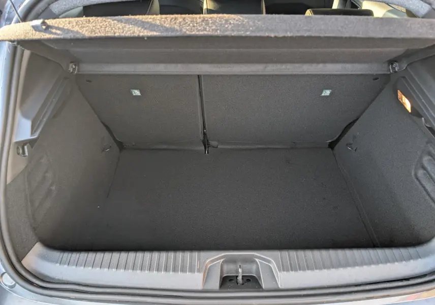 Coffre ouvert vu de l'arrière d'une Renault Clio 1.0 Tce gris schiste, espace de rangement vide et propre.