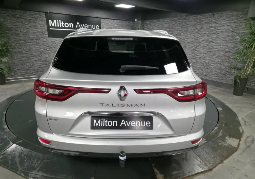 Vue arrière d'un break Renault Talisman gris avec hayon motorisé et attelage démontable, en showroom.