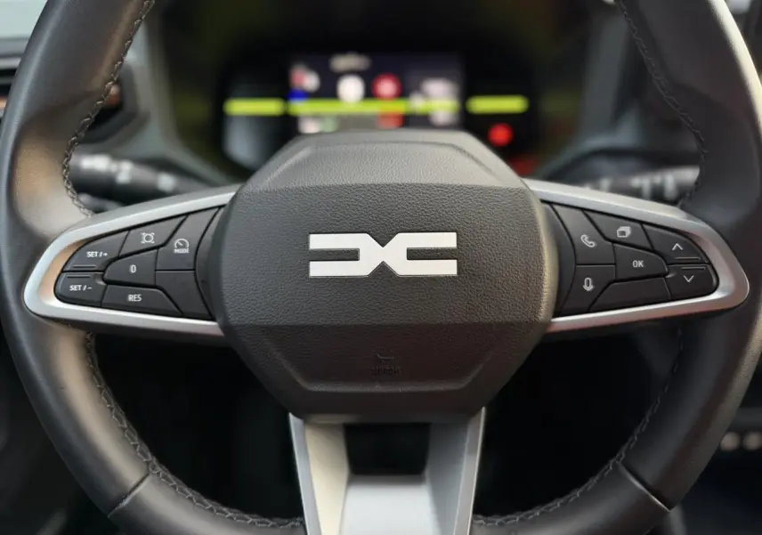 Gros plan sur le volant noir du Dacia Duster 2025 avec commandes intégrées et logo Extrême au centre.